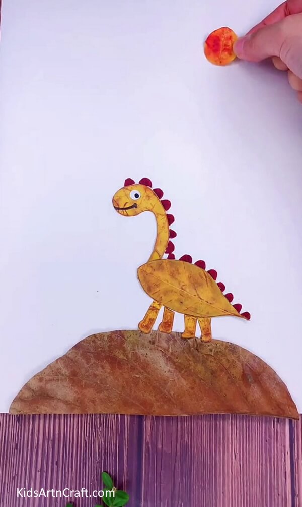 Cutting Orange Leaf with your hand- Get creative and make a dinosaur from leaves with this simple tutorial for children. 