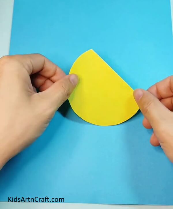 Stick yellow craft paper on blue craft paper with glue- Crafting a Bird of Paper – A Step-by-Step Walkthrough