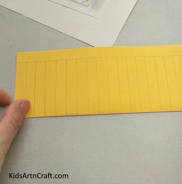 Take A Yellow Craft Paper And Make Lines to Easy Paper Fish Craft Tutorial For Kids- Learn how to construct a basic paper fish with this tutorial for children. 