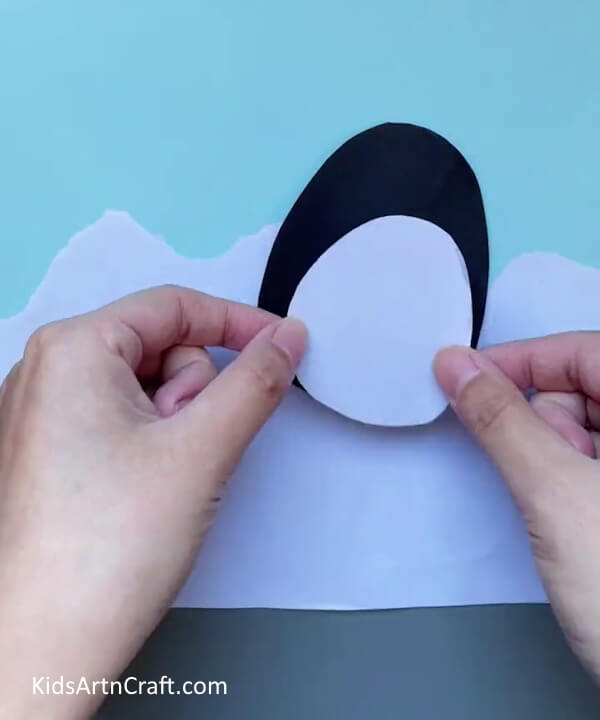 Pasting The Belly On The Egg-Putting together a paper penguin craft is a straightforward task for preschoolers