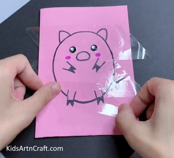 Applying Tape Over The Drawing-A DIY guide to creating a paper pig craft with kids