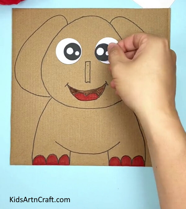 Pasting Black Circles On Eyes- Construct a Cardboard Elephant for Little Ones in Kindergarten