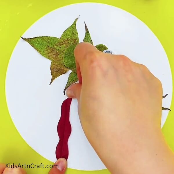 Pasting some long red leaves- Ideas For Crafting a Fishy Underwater Scene Using Leaves For Kids 