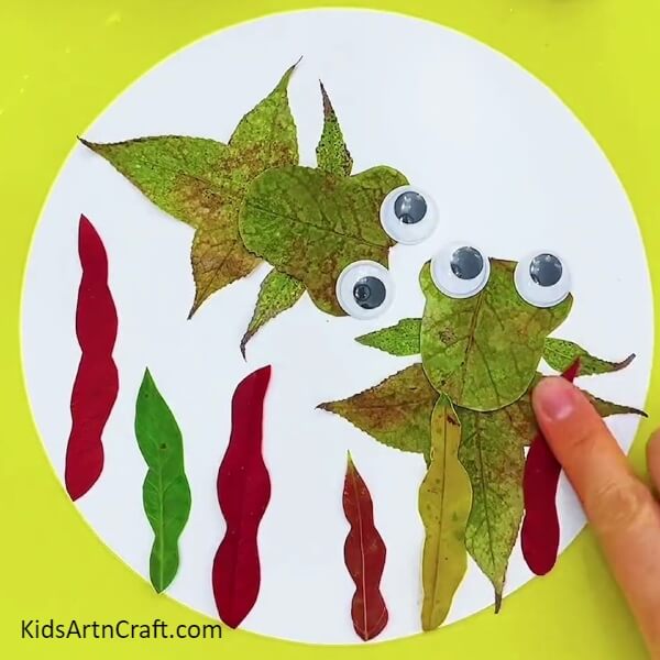 Pasting more leaves on the circumference- Teach Your Kids To Make a Fishy Underwater Scene With Leaves 