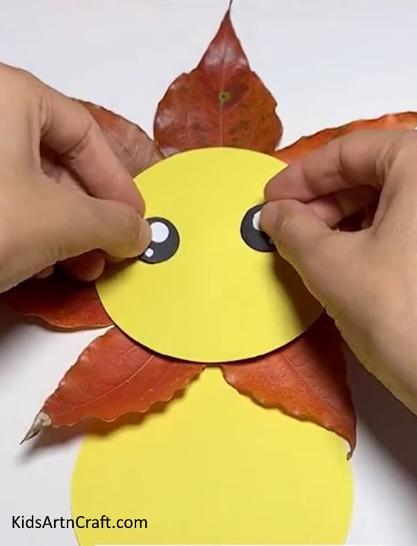 Sticking The Eyes Of The Lion- A simple, kid-friendly tutorial for constructing a lion with fall leaves