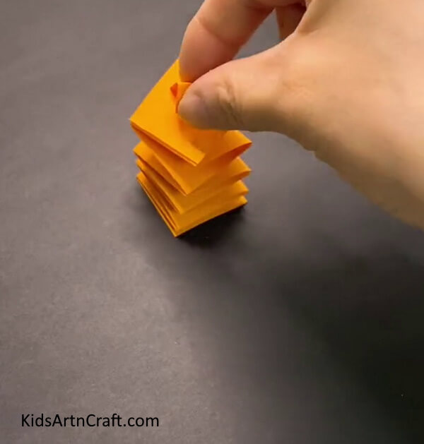 Stick The Small Triangle On The Top Surface Of The Spring- A DIY project of making a self-moving paper tiger with the aid of children