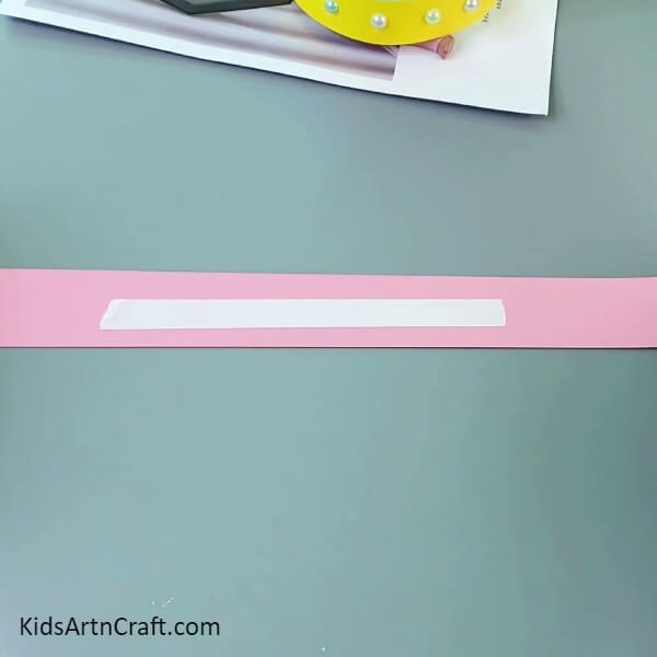 Applying Double-Sided Tape On A Pink Strip- Make a Paper Crown with this Fun Activity for Children