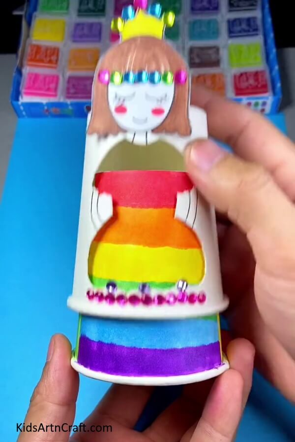 Putting designed cup into doll cup- This DIY paper cup changing dress doll craft is a great way for kids to have fun.