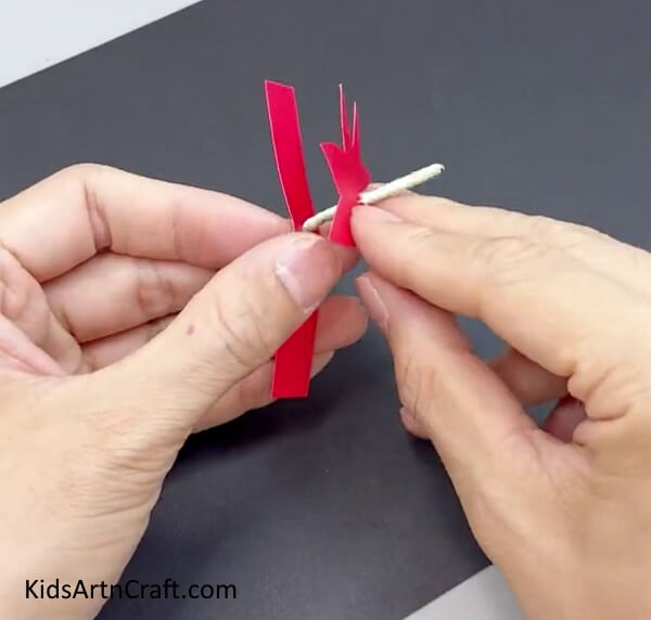 Inserting The Red Flower Inside The Paper Stick - A step-by-step guide to crafting a Paper Flower Ring with your kids