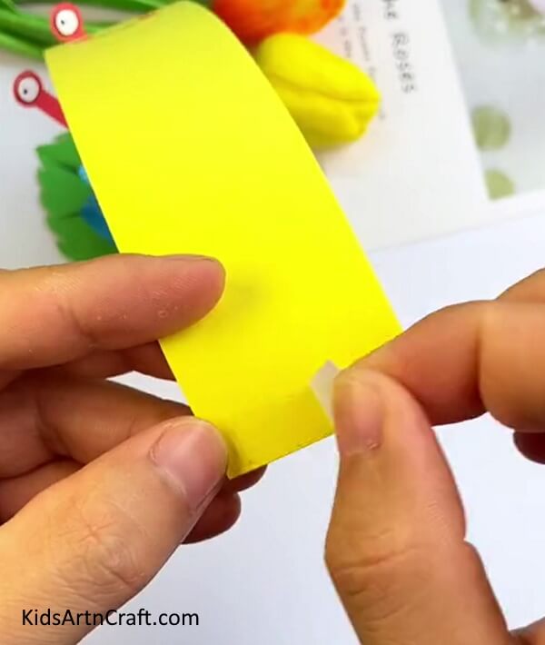 Stick a thin double sided tape on yellow craft paper- Construct a paper snail craft for your toddler to have fun with at home.