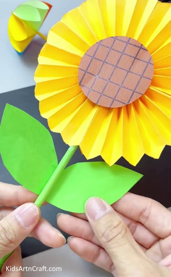 Adding Leaves To The Stem - Create a sunflower-themed artwork with paper for children.