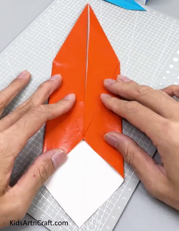 Folding The Two Corners Of The White Triangle - Teach Your Kid How to Make a Paper Sword with This Tutorial