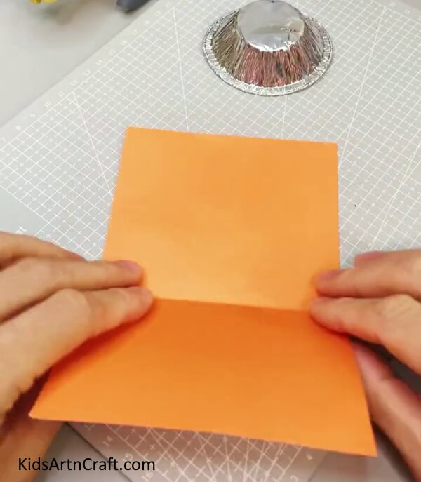 Folding The Orange Paper In Half Making a paper tiger wall hanging through a simple project.