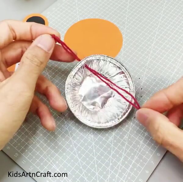 Inserting Thread Through The Hole Doing it yourself paper tiger wall hanging craft that is easy.