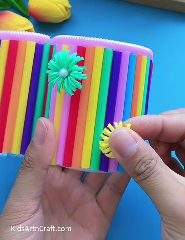 Pasting Artificial Flowers-Appropriate plastic bottles and pipe cleaners can be used to create a pencil holder.
