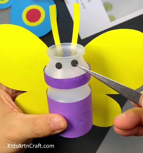 Pasting eyes on bee. Plastic Bottle and Paper Bee Craft for kids