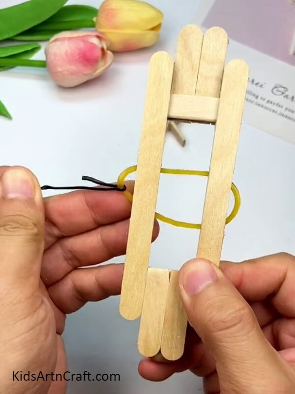 Placing the elastic rubber band between the sticks - A Tutorial for Making Toys with Popsicle Sticks for Beginners