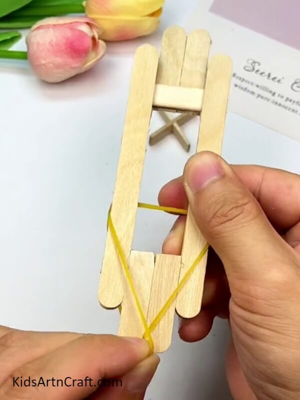 Bringing the rubber band over the sticks at the bottom - Guide For Crafting Toys Out Of Popsicle Sticks For Novices