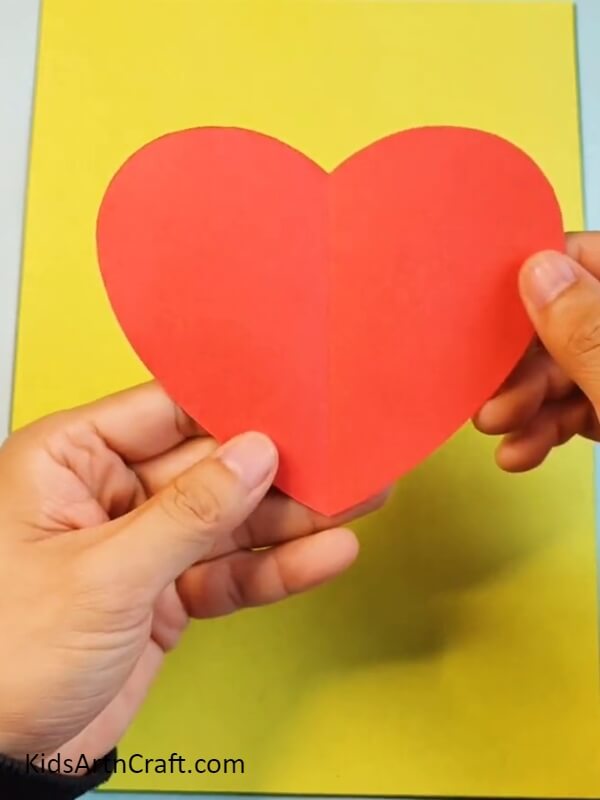 Cutting Heart Out From Red Color Craft Paper- Instructions For Making A Strawberry Project For Beginners Doing It Themselves