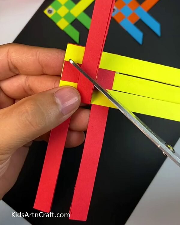 Trimming the ends of the strip- A tutorial on weaving a paper fish for kids.