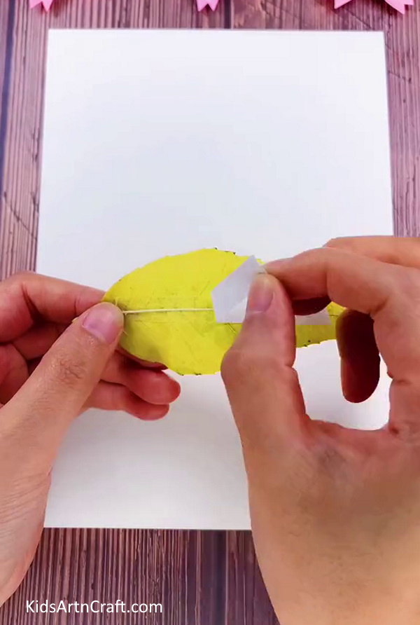 Pasting Sticky Tape On A Yellow Leaf for the Caterpillar Craft Step by Step Tutorial for kids