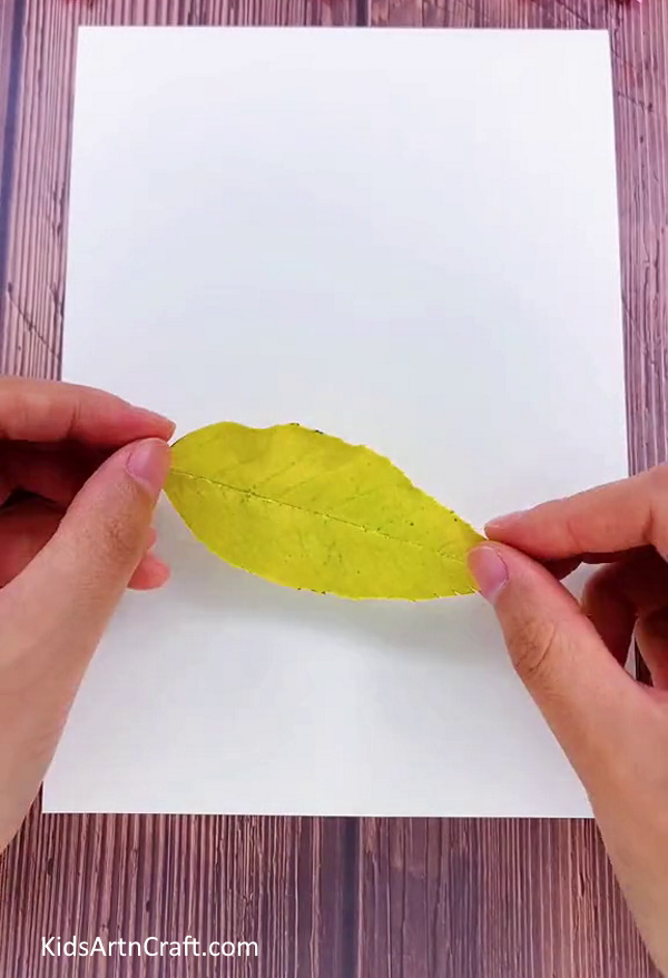 Pasting Yellow Leaf On The Middle Of The White Sheet to Easy Caterpillar Craft 