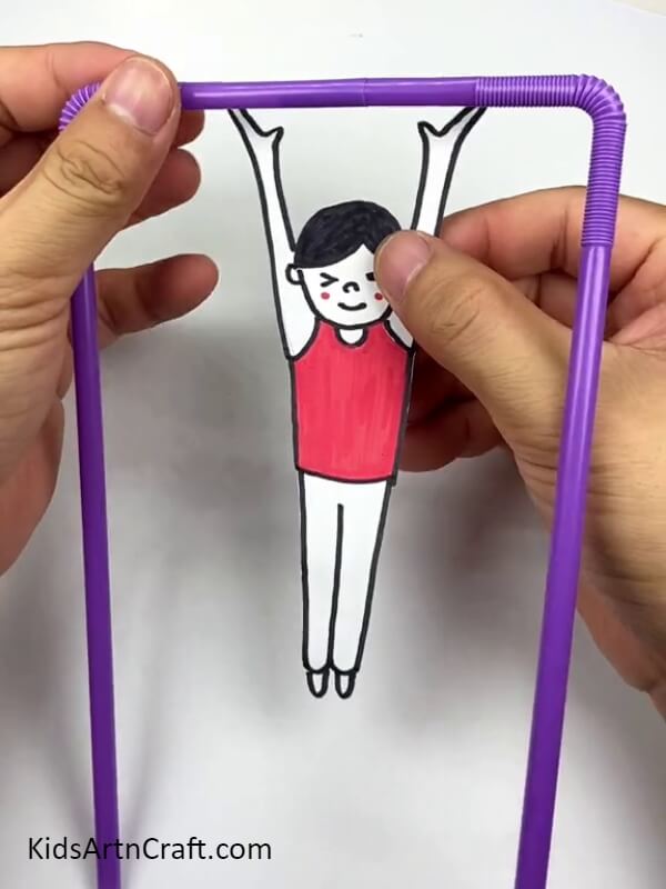 Cut the human boy figure with scissors- Step-by-step guide on constructing a hanging man with straws for children.