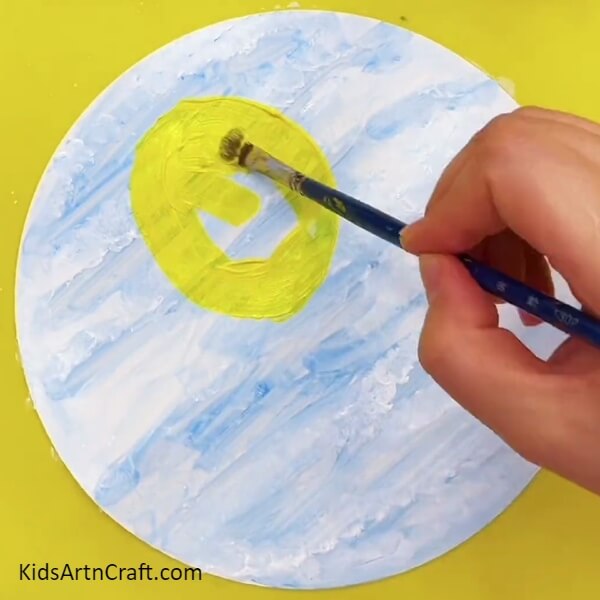 On A Canvas Sheet Make An Oval Using Yellow Paint And A Paintbrush-