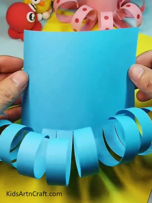 Ten rolled strips at the bottom of the sheet- Helping children make a paper octopus - an easy-to-follow guide. 