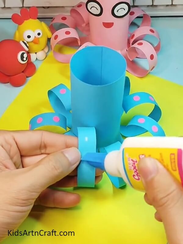 Pasting the tentacles on the legs- Step-by-step instructions for kids to make a paper octopus.