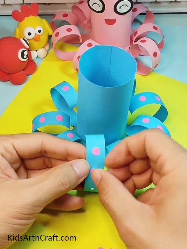 Covering all the legs with the tentacles- How to help children craft a paper octopus - a tutorial.