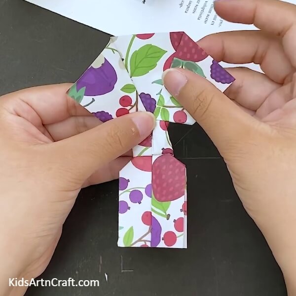 Opening the folds on the sides a little- Making a bow out of paper with origami for kids