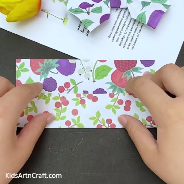 Starting the folding process- Making a bow out of paper with origami for kids