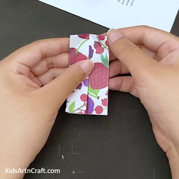 Making a vertical fold on the sheet- Crafting a paper bow with origami for kids