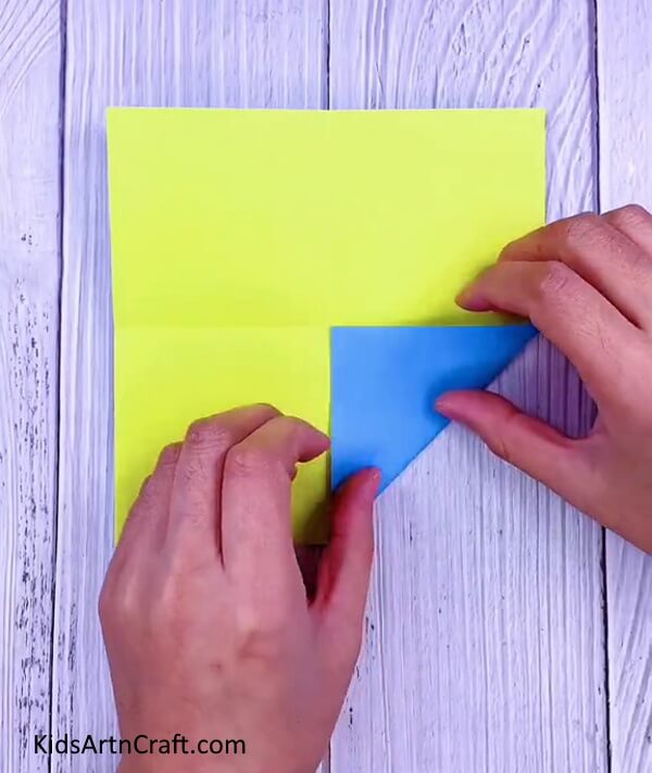 Fold one edge of the paper inwards- A simple guide to making origami Paper Paku Paku for children.
