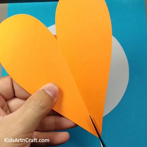 Cut the orange heart in half- A Tutorial for Crafting a Dog Face with Paper for Kids