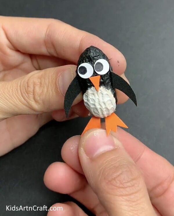 Attaching The Webbed Feet - An awesome penguin craft made with peanut, thermocol, and a paintbrush.