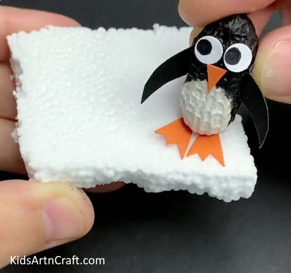 Pasting The Penguin On A Thermocol Base - An awe-inspiring penguin creation produced with peanut, foam, and a paintbrush.