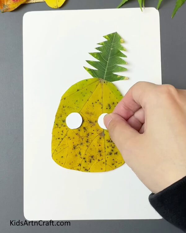 Cut Two Circles With White Craft Paper-Assembling an effortless Pineapple Artifact from fall leaves for minors. 