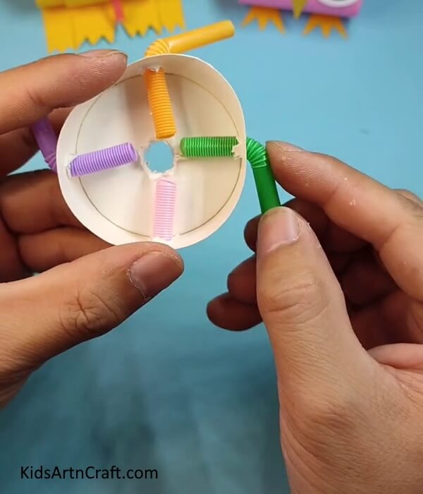 Inserting Straws In Other Two Holes-A paper cup and some straws is all it takes to create an amusing spinning toy for children.