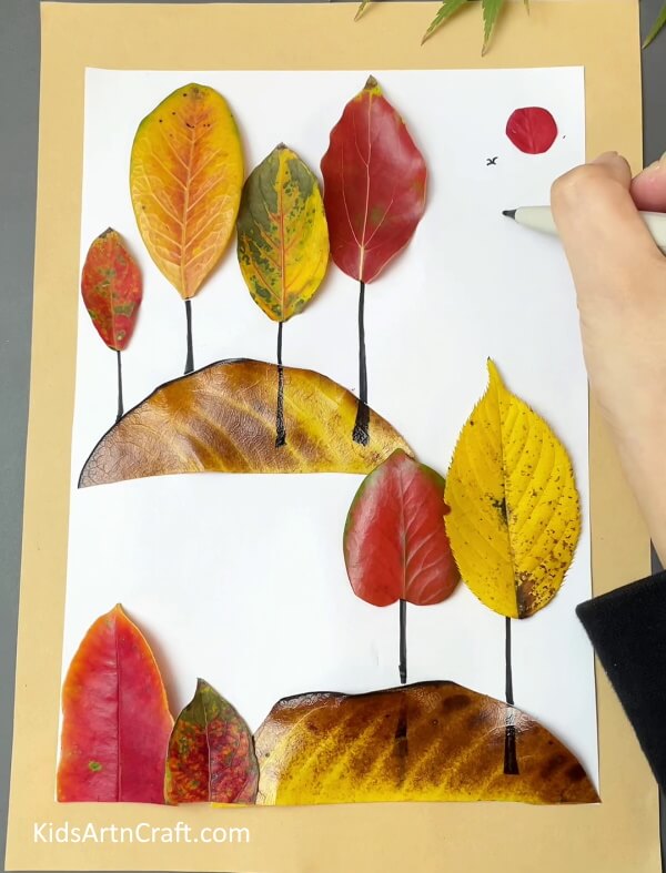 Cut circle out of leaf to form sun and draw birds- Crafting Autumn Leaves Projects For Kids - A Tutorial