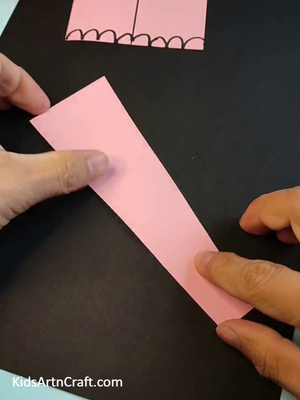 Cutting lengthy piece of pink paper for making trunk- Simple Paper Elephant Projects For Little Ones 