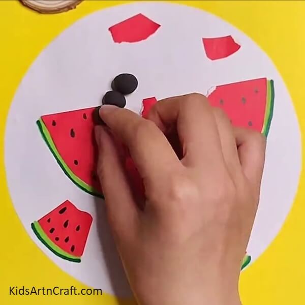 Cutting small circles from black paper- An Artistic Experience – Watermelon Ants and Youngsters