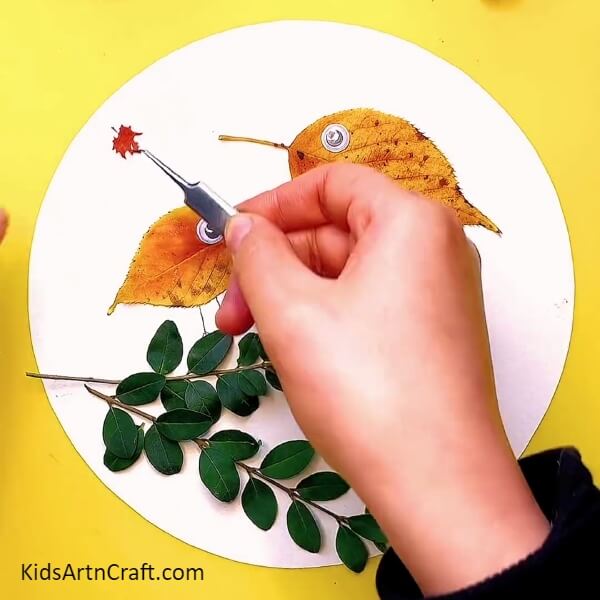 Sticking some decorative fall leaves in the surrounding to give some fall vibes - Follow these steps to make a Fall Leaves Bird with your hands - a tutorial for kids.