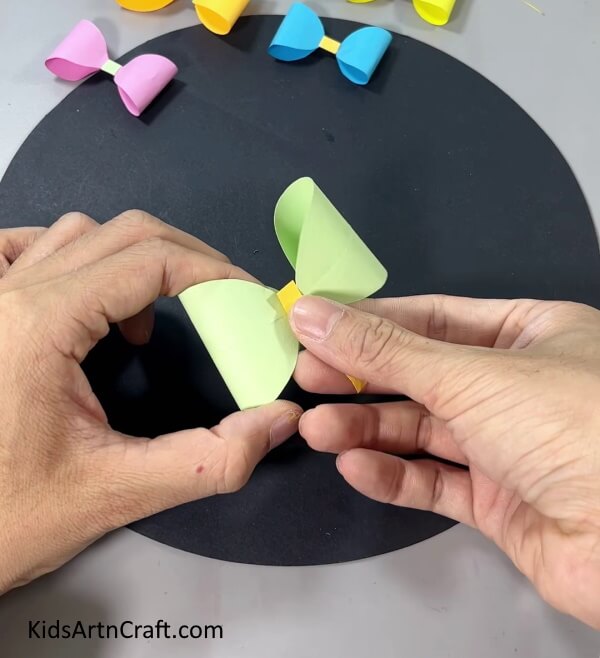 Pasting A Paper Strip In the Middle - Kids can learn to make a paper bow quickly with this simple tutorial.