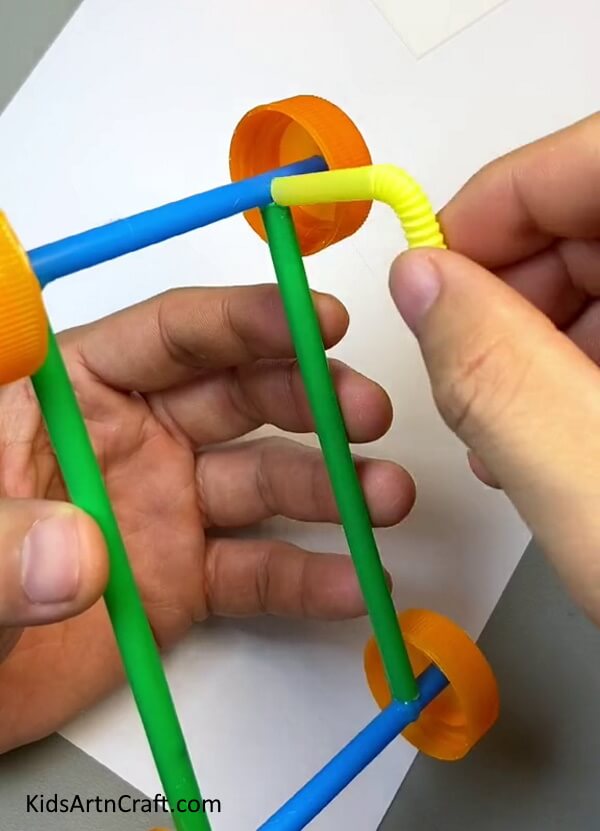 Pasting A Cut Out Bent Part Of Yellow Straw-Constructing a Toy Automobile with Straws - Tutorial for Kids