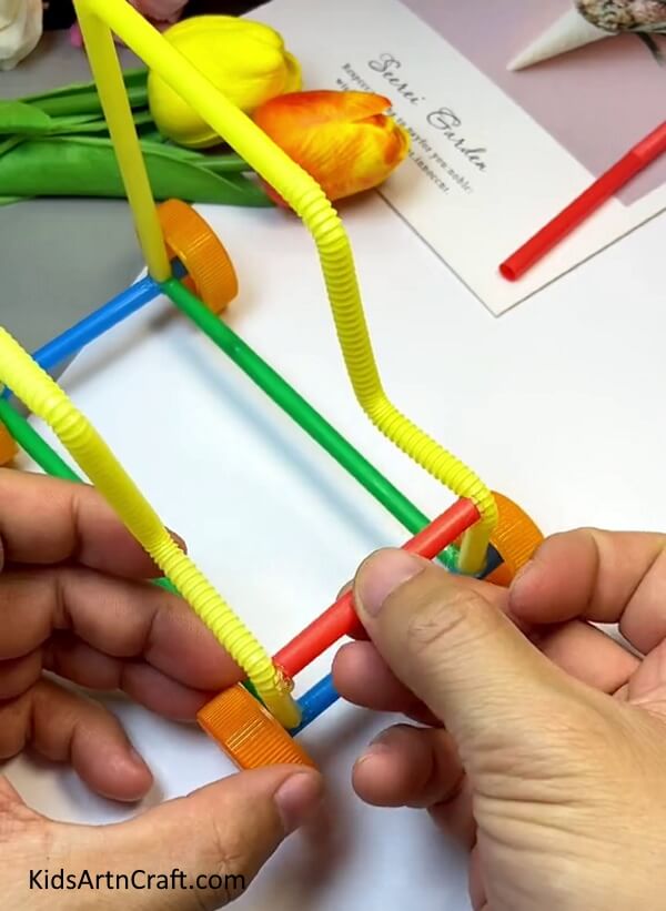 Pasting A Red Straw In The Front-Learn to construct a Toy Car from a straw with this straightforward guide for children