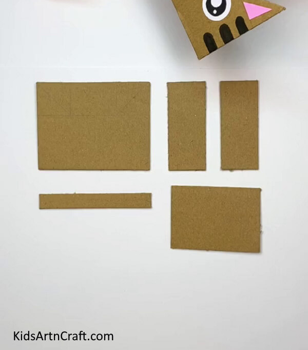 Cutting Out Cardboard Pieces-Learn the steps to constructing a Cardboard Cat with this straightforward guide for children 