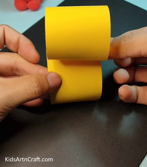 Pasting the two rolled strips together- Creating a paper duck out of strips for kids.