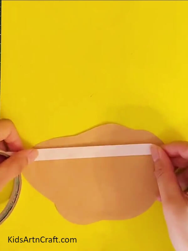 Pasting Piece Of Brown Paper On Yellow Craft Paper-Crafting a Paper Lily Flower For Kids